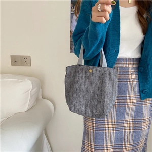 Detail of herringbone wool handbag with grey fabric handle and gold button accent