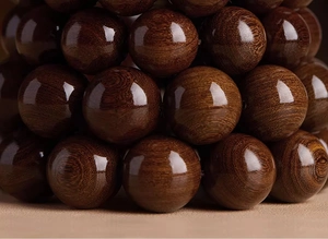 Macro shot of polished dark brown wood beads showing natural golden silk grain and texture