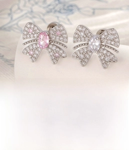 Detail of silver bow cartilage stud earrings with zircons and flat back screw design