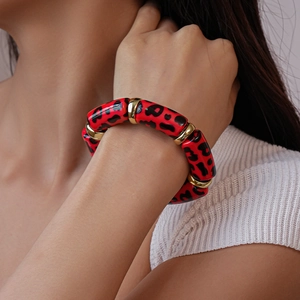 Close-up of red leopard print acrylic bracelet with gold accents on a model's wrist
