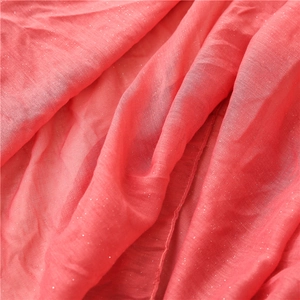Macro detail of breathable coral pink scarf fabric with subtle metallic shimmering thread