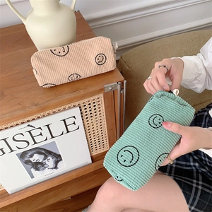Detail of corduroy makeup bags with smiley print in beige and green colors