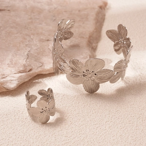Detail of silver floral bangle and ring set with textured petals on natural stone