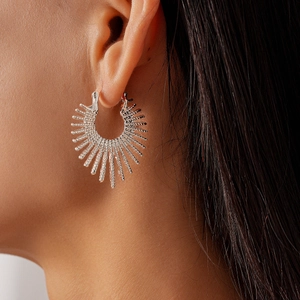 Close-up of silver irregular sunburst earrings with a textured metal finish on a model