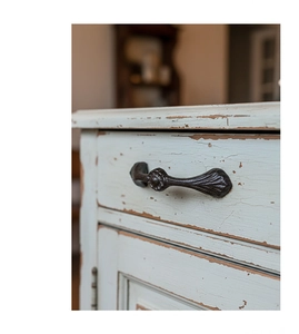 Detailed close-up of retro cast iron drawer handle with vintage floral texture on wood