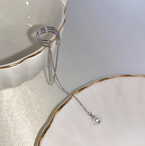 Detail of silver long chain tassel ear cuff featuring a round pearl pendant on porcelain