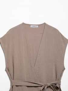Dettaglio dello scollo a V e etichetta di marca di un top gilet marrone in lino