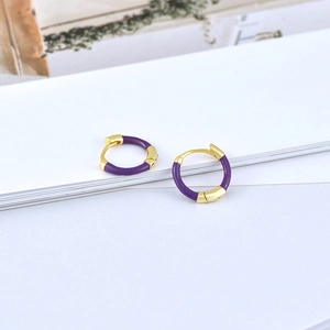 Close-up of gold and purple enamel huggie hoop earrings on a minimalist white backdrop