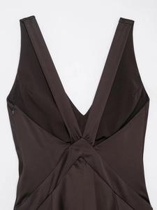 Detail of elegant chocolate satin dress featuring deep V-neck and crisscross pleated design