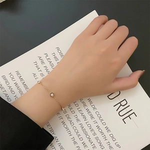 Elegantes Armband in Roségold mit drei Zirkonia-Steinen auf einem minimalistischen Buch