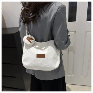 Detailed shot of white corduroy tote bag with small round pouch and leather fashion tag