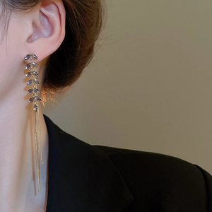 Detailed view of long gold tassel earrings with purple-grey zircon stones on a model