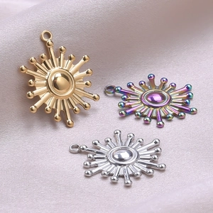 Detailed view of three sunburst pendants in gold silver and rainbow finishes on silk