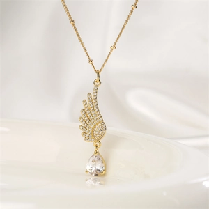Close-up of golden angel wing necklace with crystal inlay and teardrop gem on silk