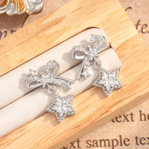 Sparkling silver bow and star stud earrings with zircon stones in a wooden jewelry box