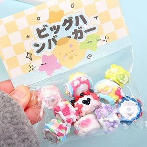Macro shot of colorful acrylic cat paw beads with heart and cake designs in packaging