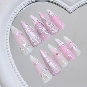 Pink cat eye stiletto press-on nails with silver bows and pearls on a heart mirror