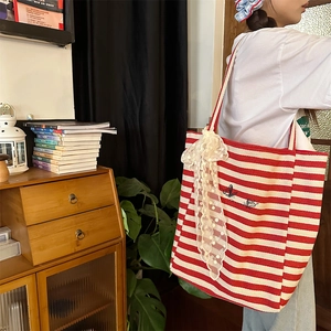 Detail of red striped canvas tote bag featuring lace bow and butterfly embroidery