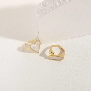 Detail of adjustable gold rings with heart shell inlay and zircon accents on white stone