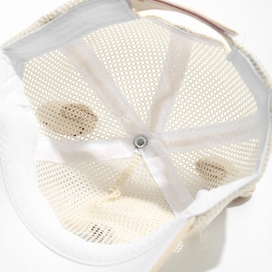 Détail macro du tissu en maille respirante et sangles intérieures de la casquette bébé