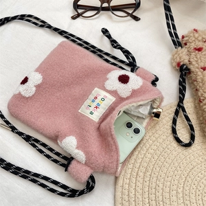 Close-up of pink plush crossbody bag with floral embroidery and striped rope strap