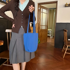 Detail van de blauwe gewatteerde geplooide shopper gedragen door een model in een retro café