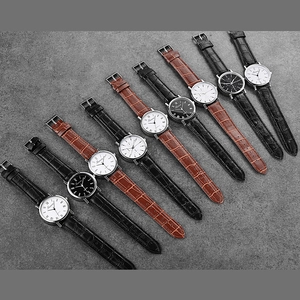 Flat lay showing variety of minimalist quartz watches with leather straps on stone surface