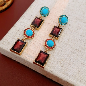 Macro view of vintage earrings with green and red stones on a linen background