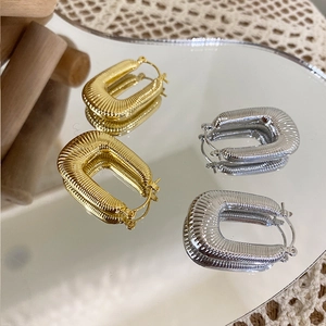 Detailed view of U-shaped braided metal earrings with gold and silver threaded texture