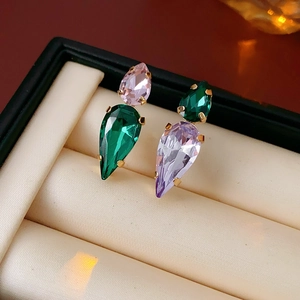 Detailed shot of teardrop earrings with pink purple and emerald zircons in gold setting