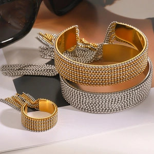 Detail of mixed-metal gold and silver mesh bangles with tassels on textured background