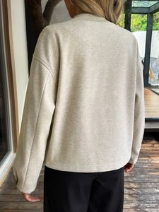 Vista posteriore della giacca corta in lana beige con spalle scese e tessuto spesso