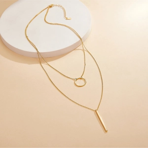 Detail of minimalist double-layer gold necklace featuring circle and bar pendants