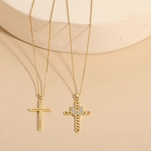 Detail of 14K gold plated cross and bow pendants with sparkling zircon on stone base
