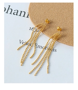 Vue macro de boucles d'oreilles à franges perlées dorées avec texture métallique