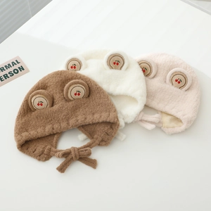 Détail des bonnets d'hiver en peluche pour bébé avec broderie cerise et protège-oreilles