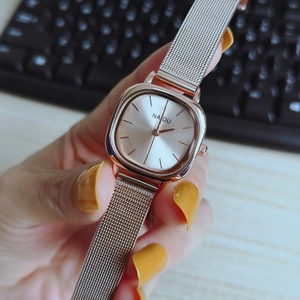 Detailed macro of rose gold square quartz watch with Milanese mesh strap on wrist