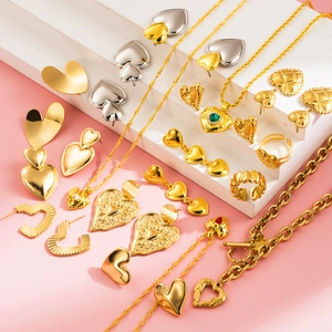 Elegant gold and silver heart-shaped jewelry set with necklace and rings on pink stairs