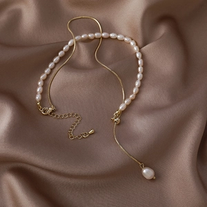 Detail of baroque freshwater pearls and gold chain necklace on champagne satin fabric