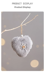 Close-up of heart-shaped grey plush ornament with wooden snowflake and rustic twine
