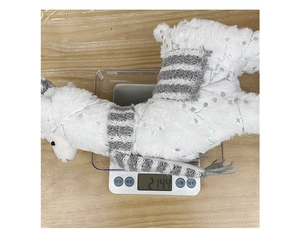 Gedetailleerde gewichtsweergave van een witte pluchen alpaca met sjaal op een weegschaal