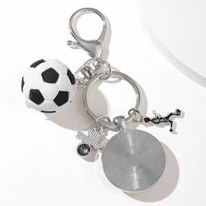 Metal soccer keychain with football player silhouette and cross charm on white background