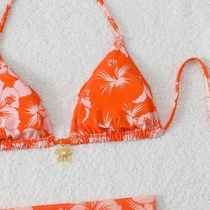 Detail of orange bikini top with tropical hibiscus print and gold flower pendant charm