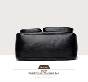 Detail view showing the flat bottom and litchi texture of the black leather handbag