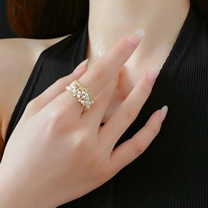 Dettaglio di un anello intrecciato con perle placcato oro indossato per un look chic