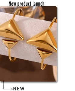 Detailed macro view of 18K gold plated triangular spring bracelets on a beige pedestal