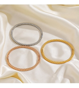 Detail view of gold, silver, and rose gold beaded bangles on elegant silk fabric background
