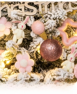 Detail of pink wool felt ice cream and rabbit ornaments on a snowy Christmas tree