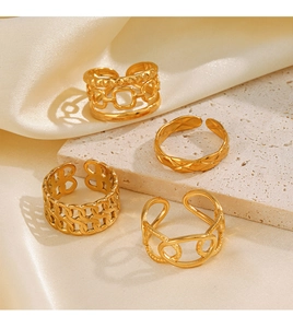 Detail of four gold-plated stainless steel chain rings on textured stone and silk