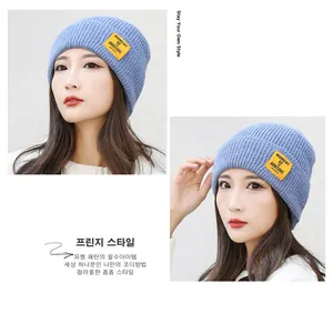 Detail of light blue knit beanie showing the yellow woven label and soft ribbed texture